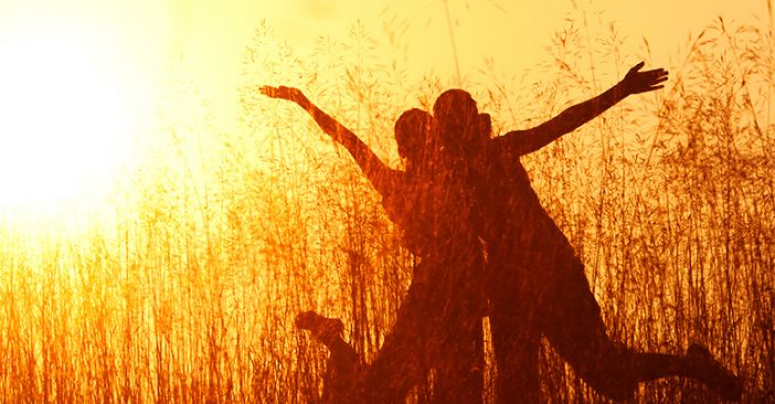 Silhouette of two people happy at a field in the sunset